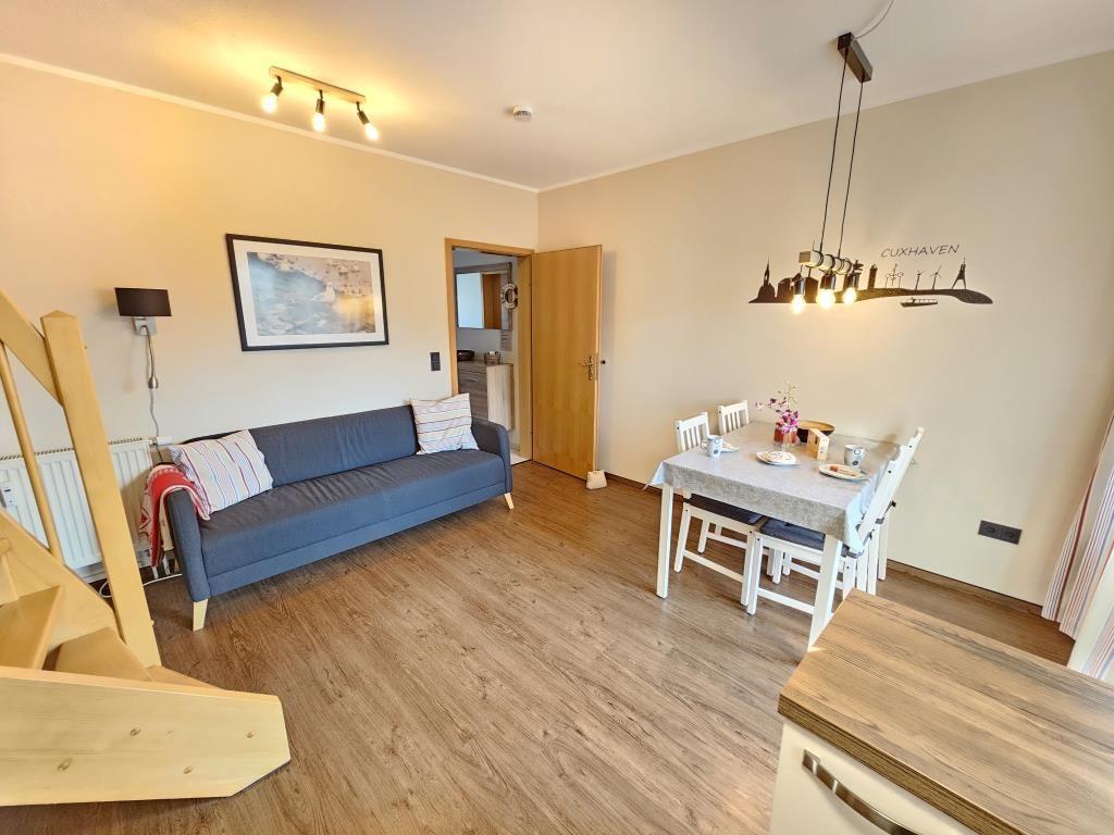 Wohn- und Essbereich mit Sofa, Tisch und Stühlen. Holzboden und Wanddekoration.