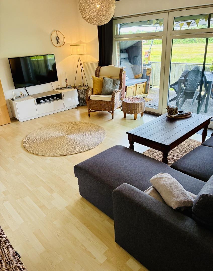 Wohnzimmer mit Sofa, Fernseher und Terrasse