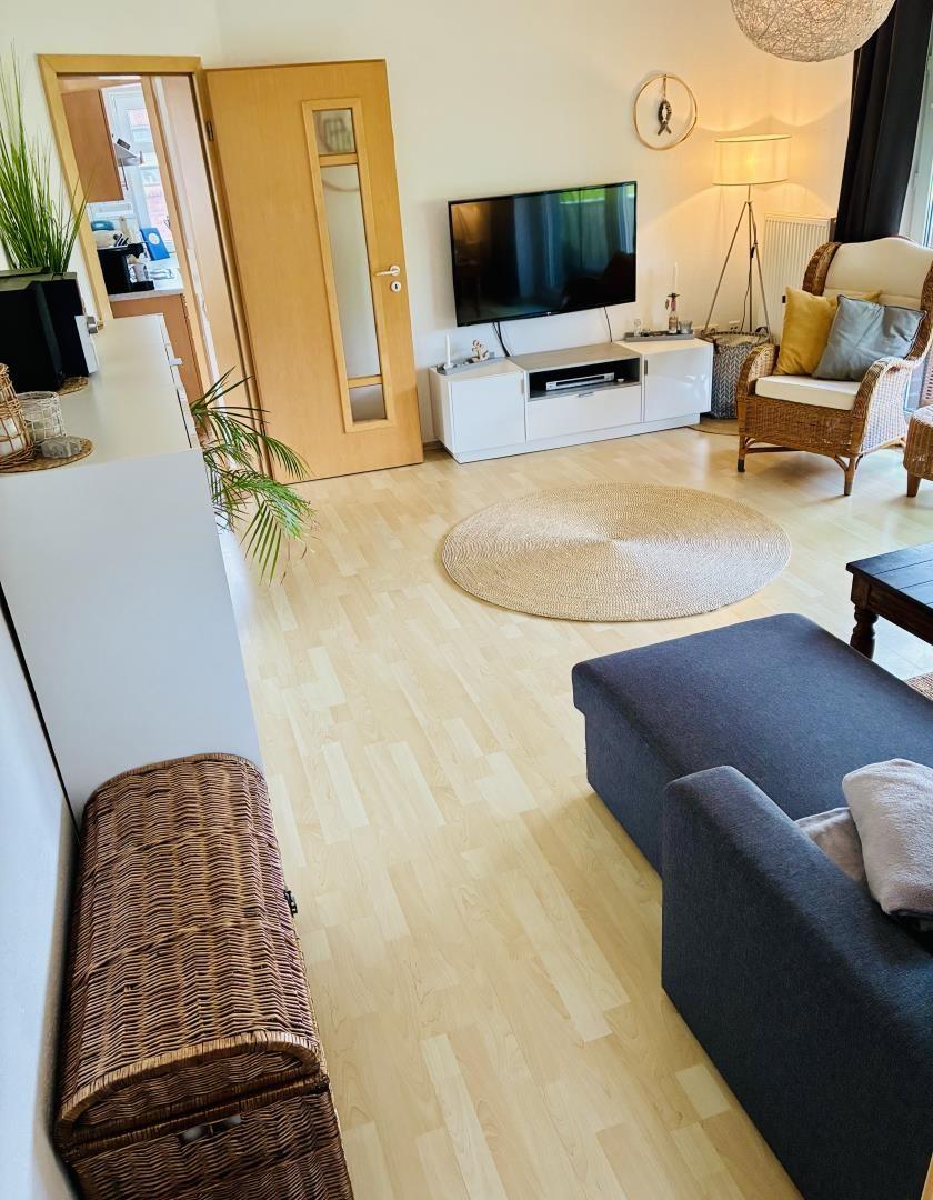 Wohnzimmer mit Sofa, Fernseher und Holzboden.