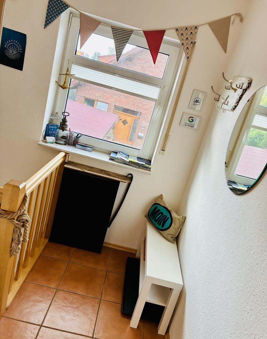 Eingangsbereich mit Fenster, Bänkchen und Dekoration.