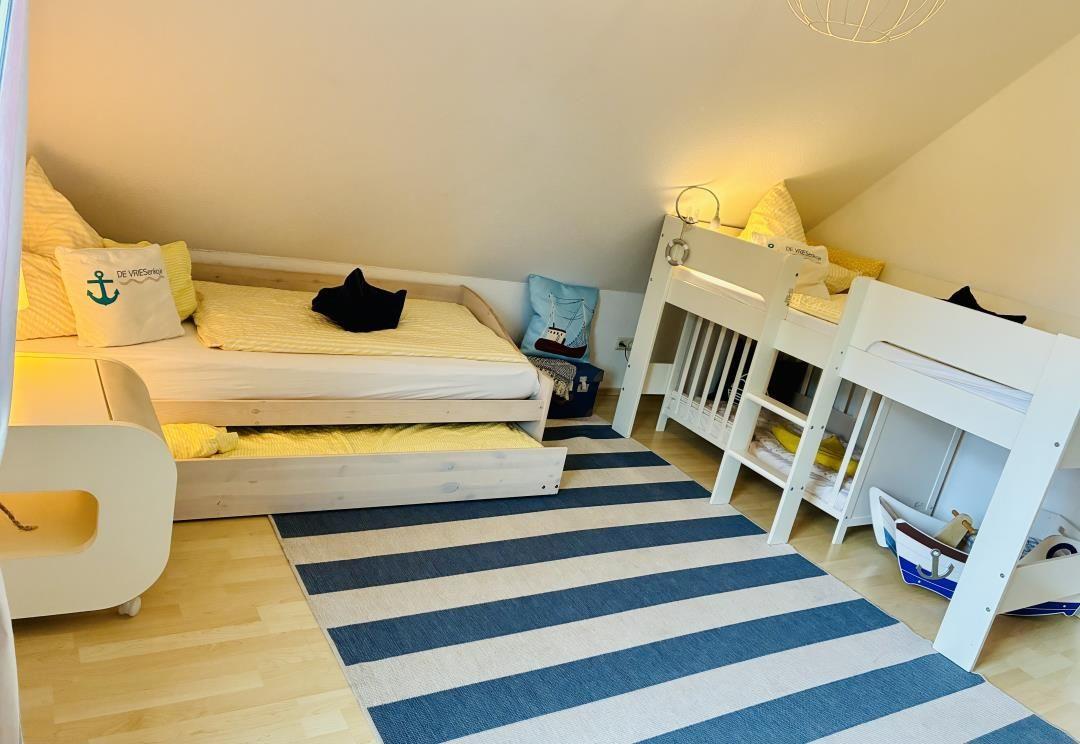 Zimmer mit Doppelbett, Krippenbett und gestreiftem Teppich