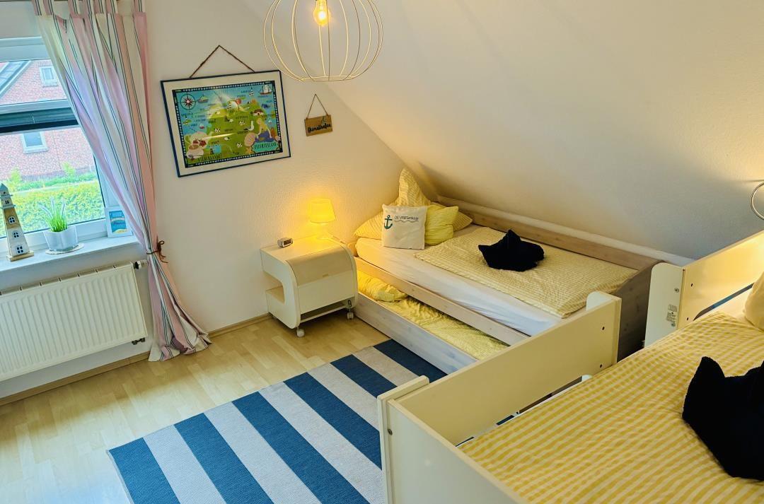 Zimmer mit zwei Betten, Fenster, Lampe und Wandbild.