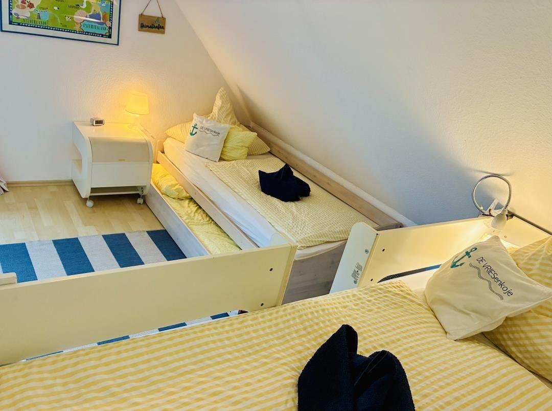 Zimmer mit zwei Betten, Nachttisch und Wandbild. Dachneigung sichtbar.