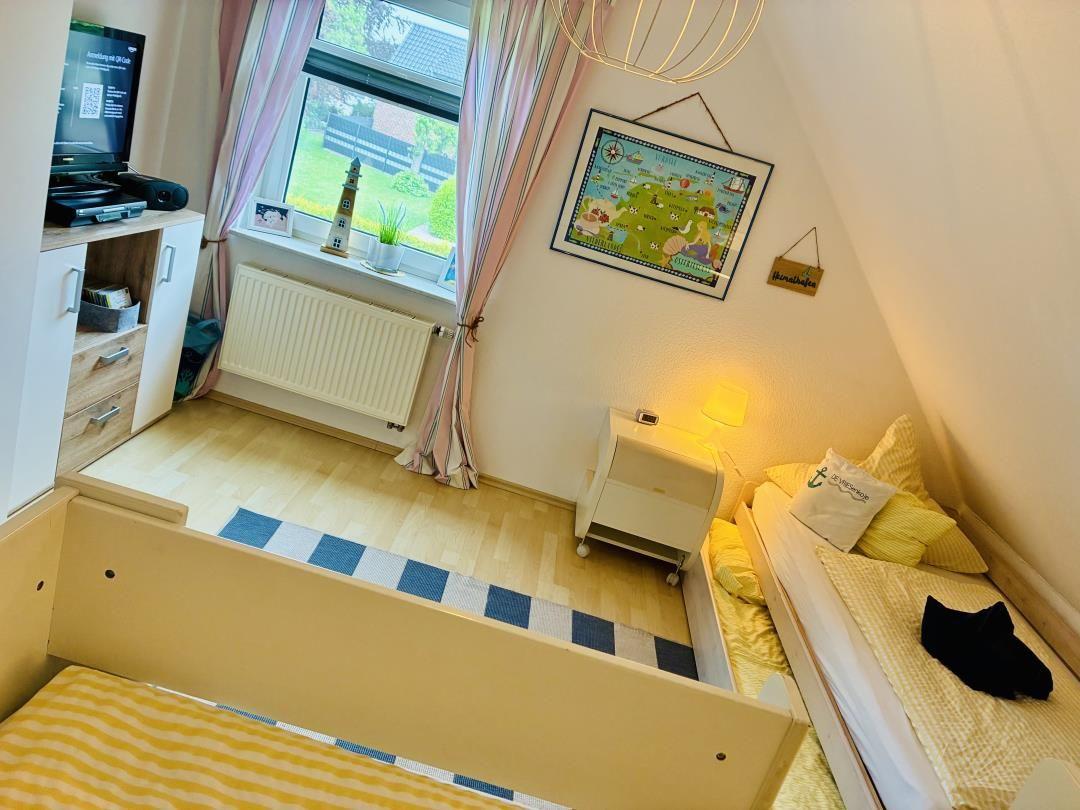 Schlafzimmer mit zwei Betten, Fenster, Schrank und Wandbild.