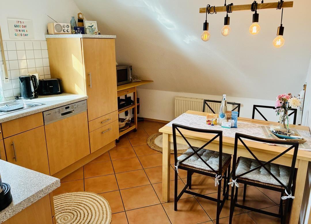 Küche mit Esstisch, Holzmöbeln und Pendelleuchten an schräger Decke.