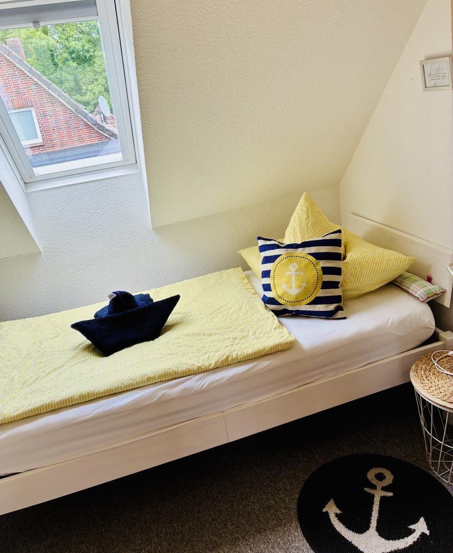 Schlafzimmer mit Nautik-Dekoration und Dachfenster. Bett mit Kissen und Schiffstuch.