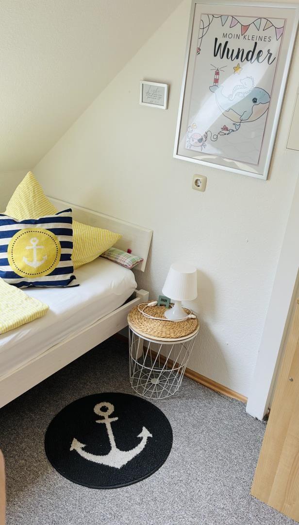Schlafzimmer mit Bett, Kissen, Teppich und Wandbild.