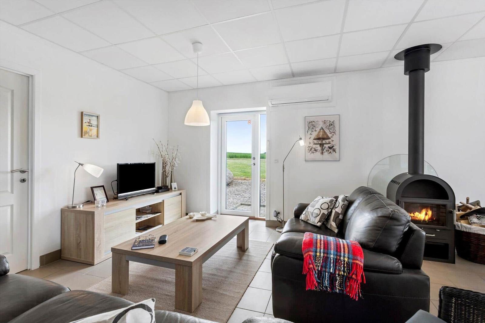 Living room with sofa, fireplace, and TV. Door leads outside.