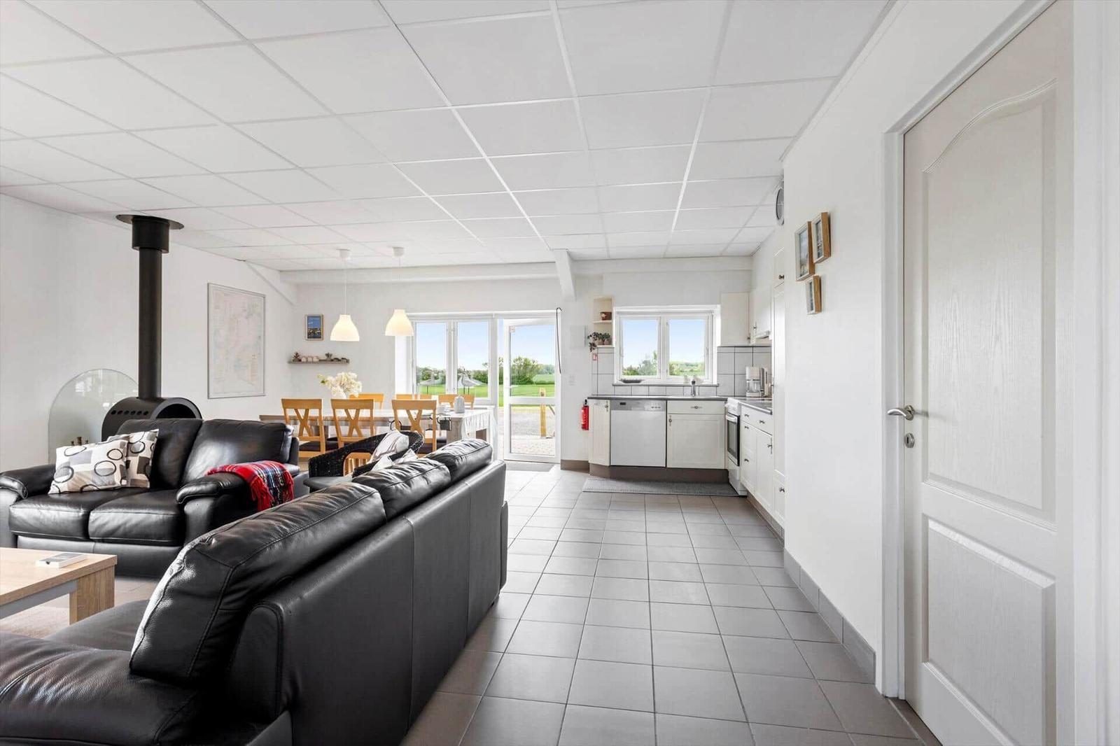 Living and dining area with kitchen, black leather sofas, and terrace door.