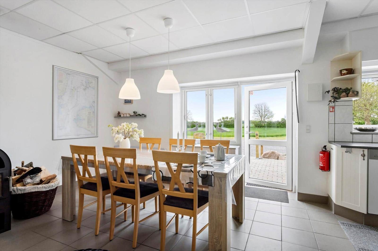 Dining room with table, chairs, and view of green landscape.