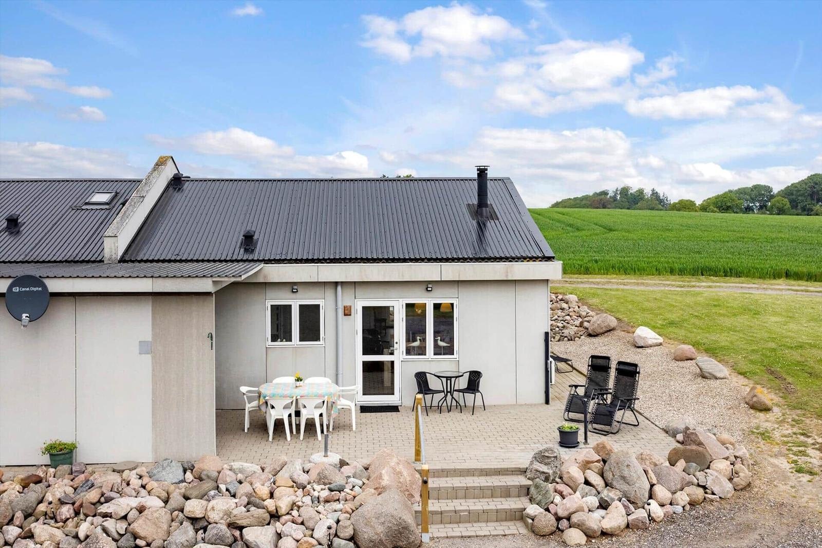 Modern villa with terrace, garden, and view of fields.
