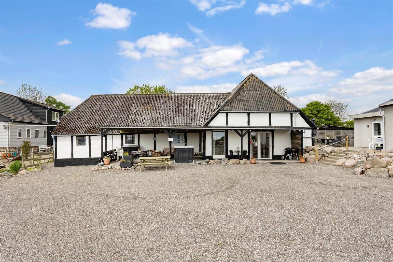 Holiday home with white facade and black timber frame, large yard and terrace.