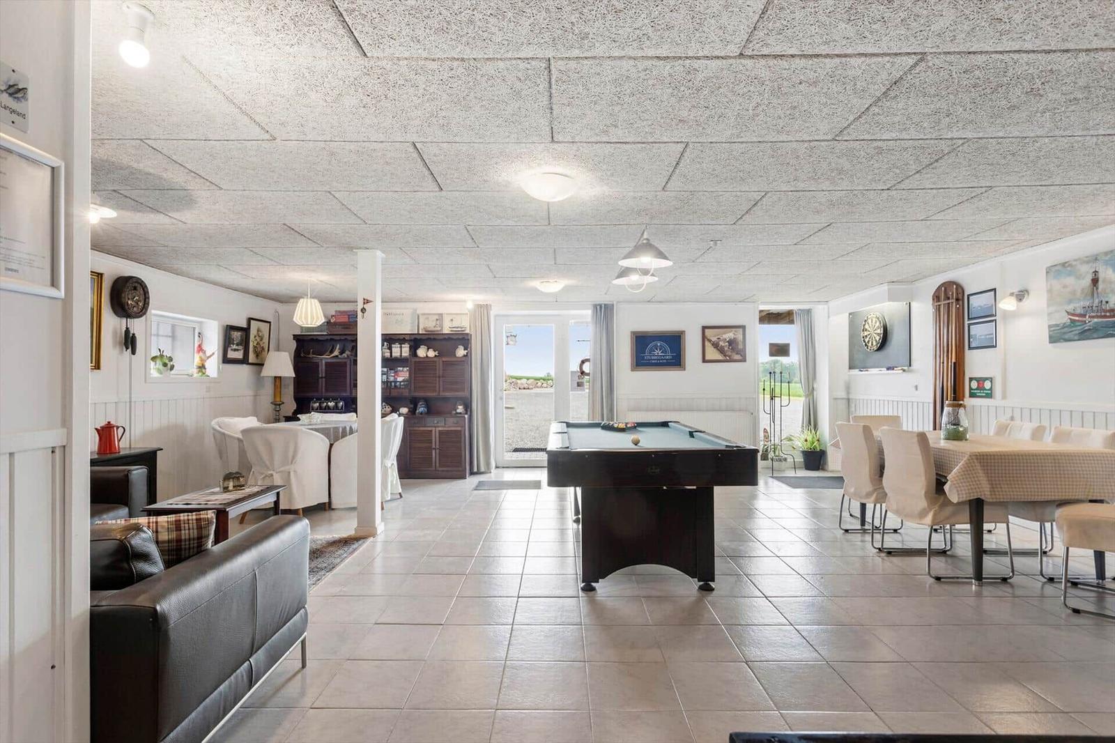 Large room with pool table, dining table, and living area. Tile floor and light walls.