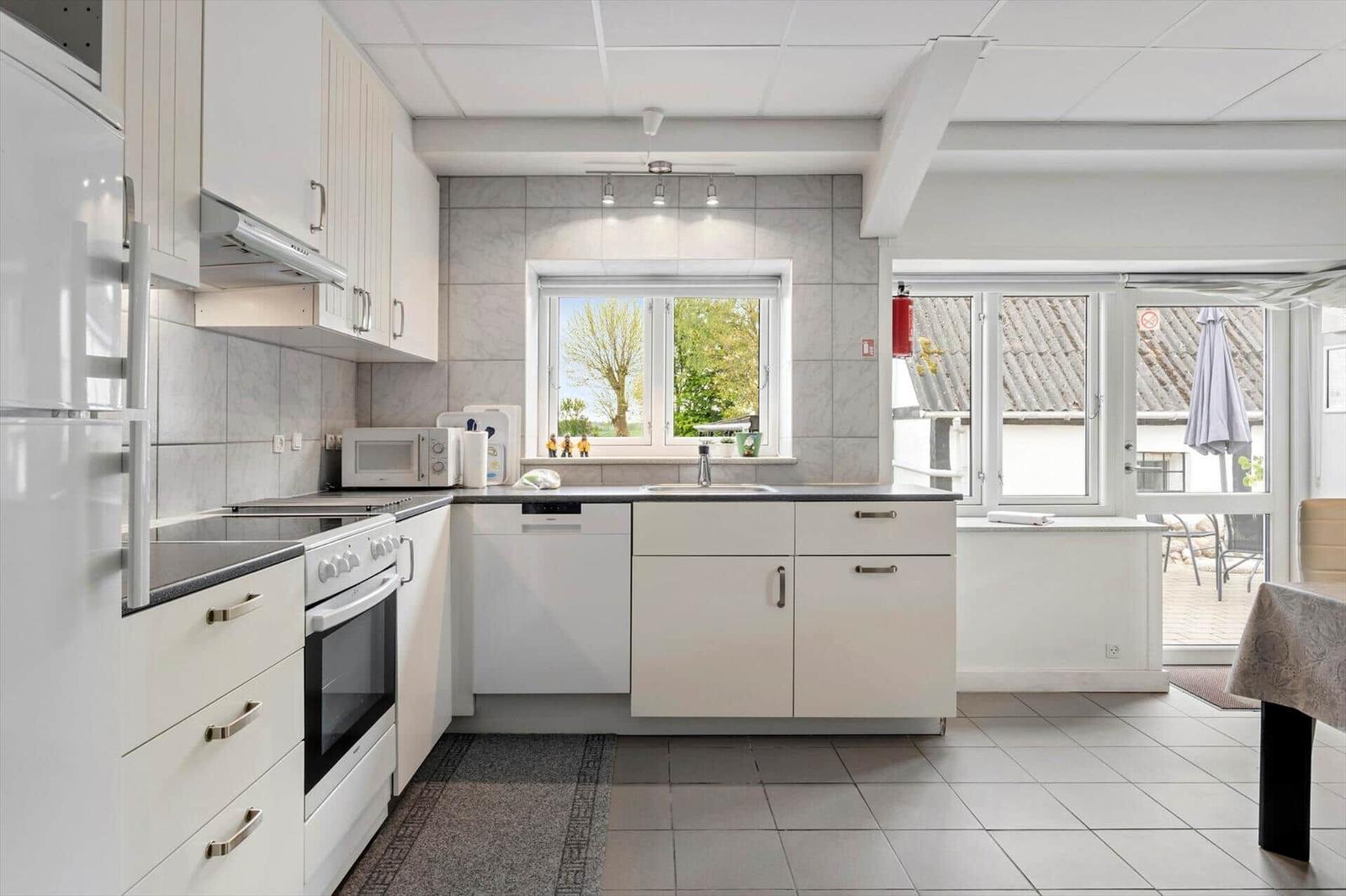 Kitchen with white cabinets, countertop, and window to the garden.