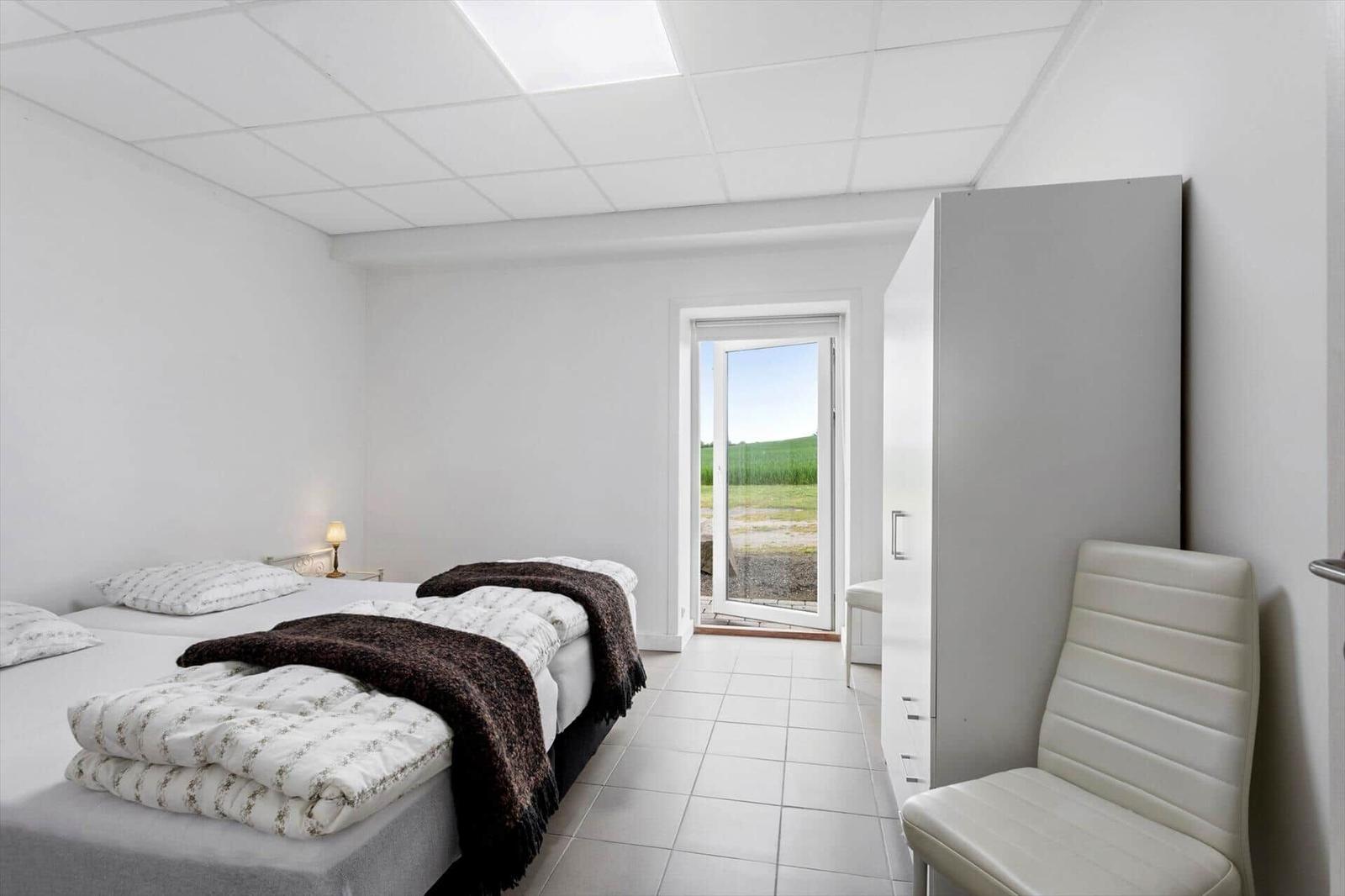 Bedroom with bed, chair, and door to the garden.