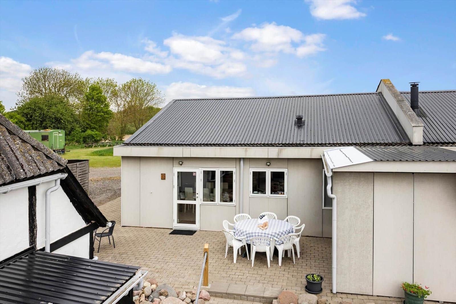 A house with a terrace and a white table set outside under a blue sky.