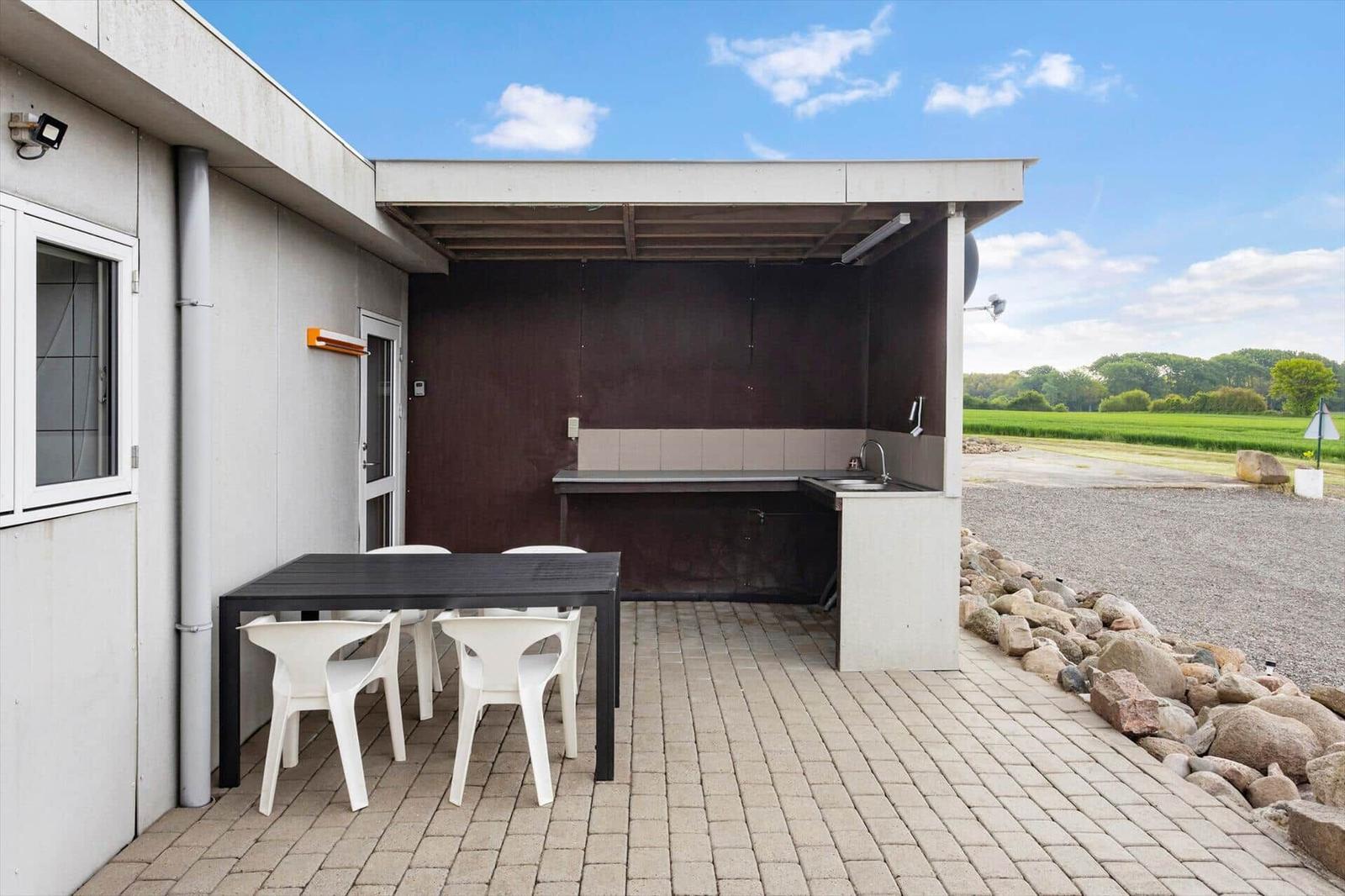 Outdoor area with grill station, table, and chairs. View of fields and sky.