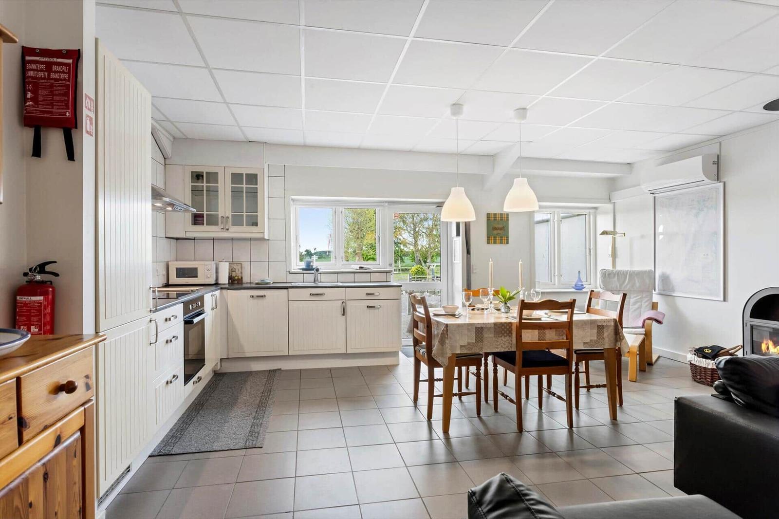 Kitchen with dining area and fireplace. Wooden table, white cabinets, and windows to the garden.