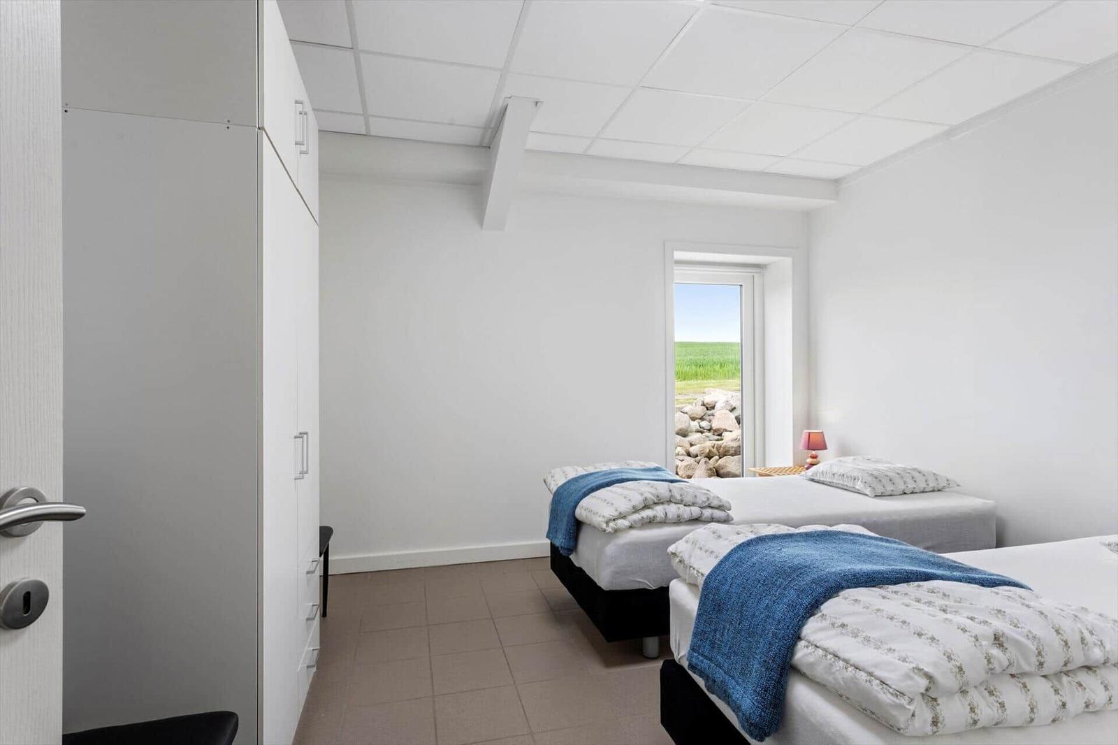 Two beds with blue blankets and view of green field