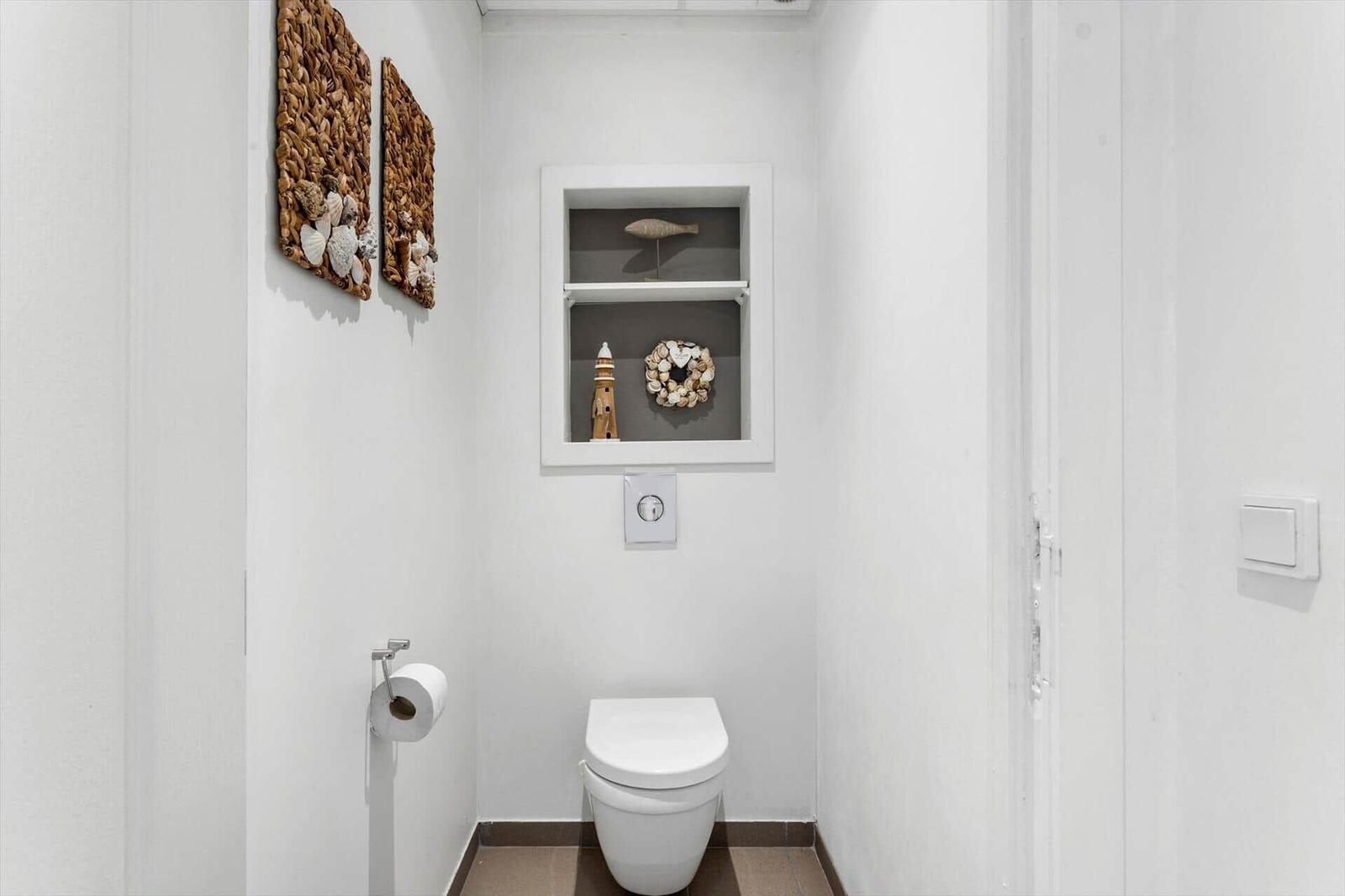 Bathroom with toilet, wall niche, and decorative wall objects.