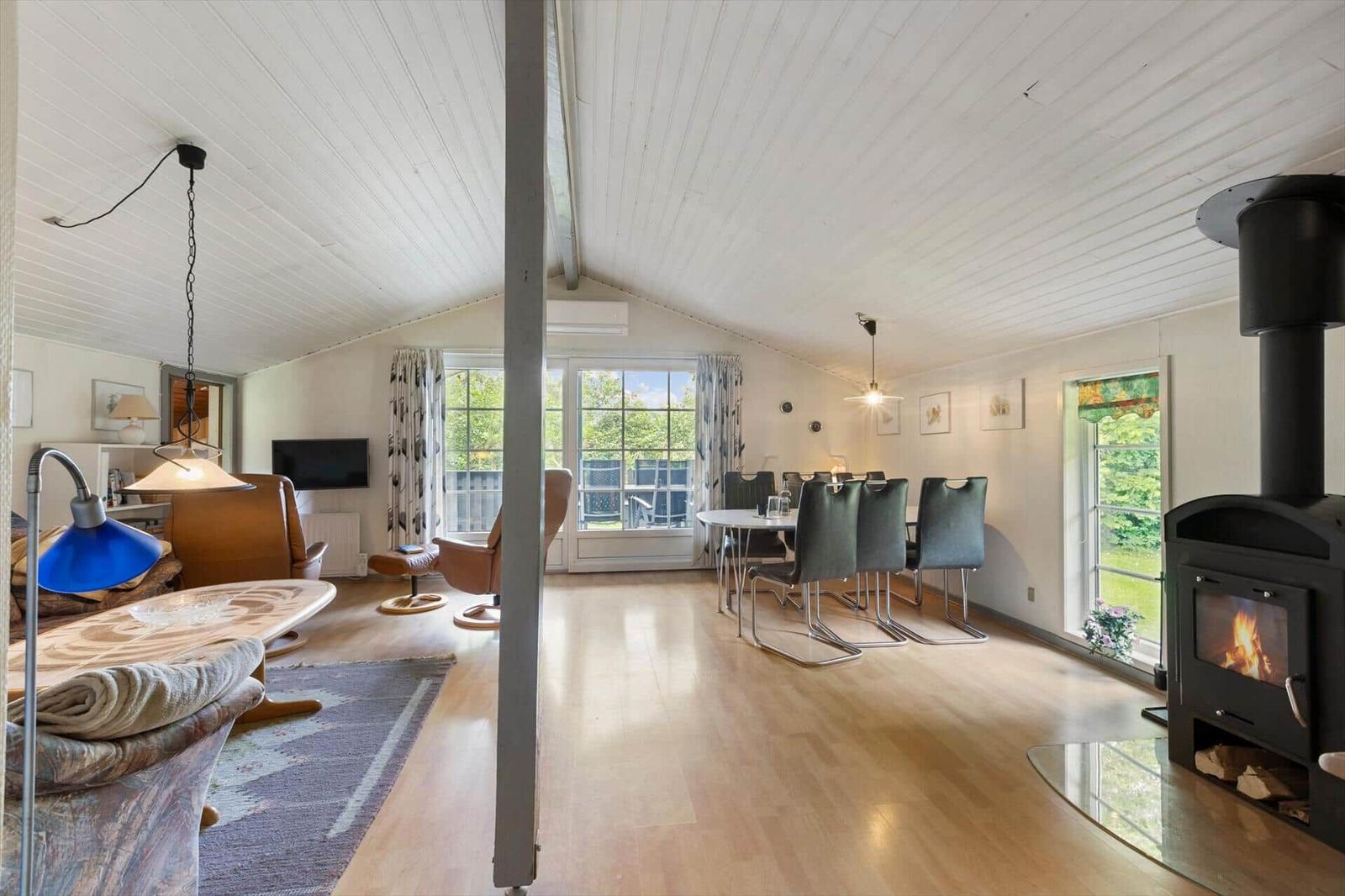 Living and dining area with fireplace, wooden floor, and large windows.
