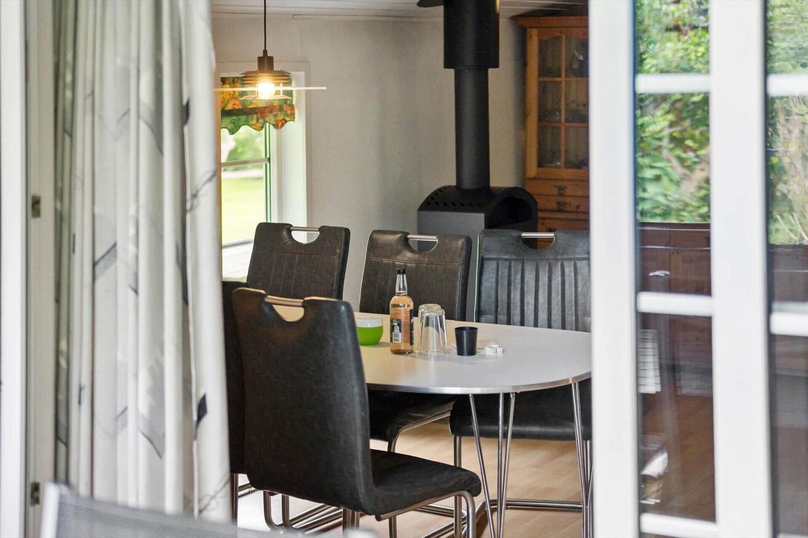 Dining table with chairs, fireplace, and window with view of greenery