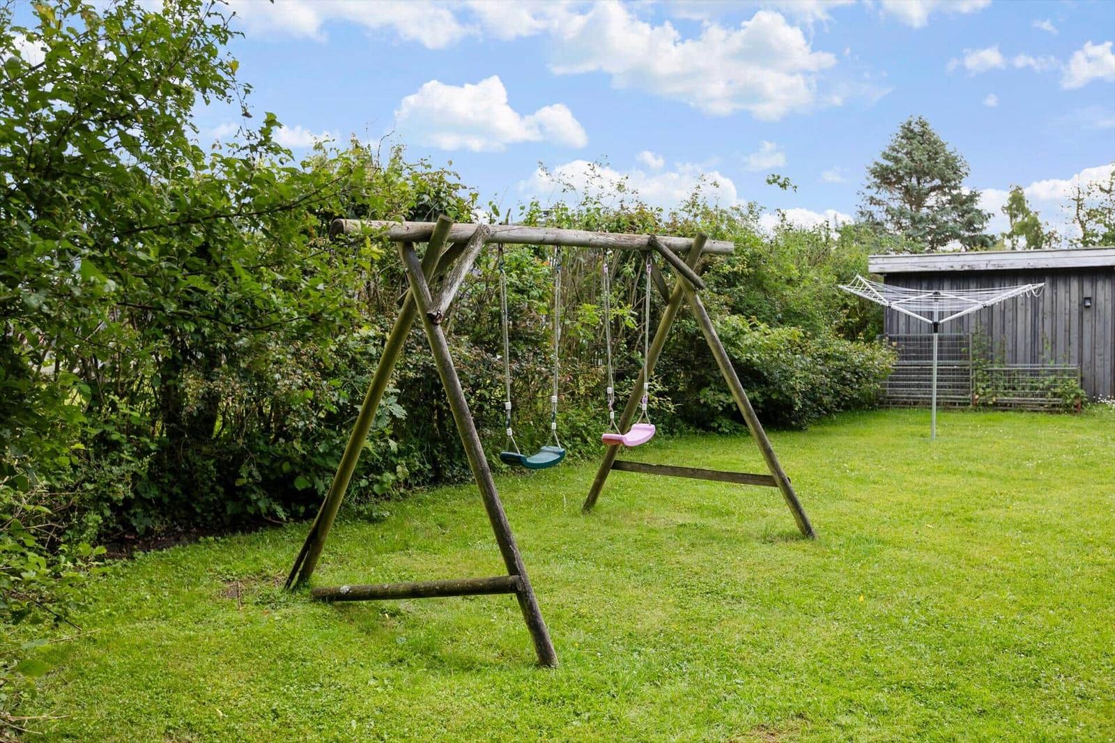 Wooden swing with two seats in the green garden.