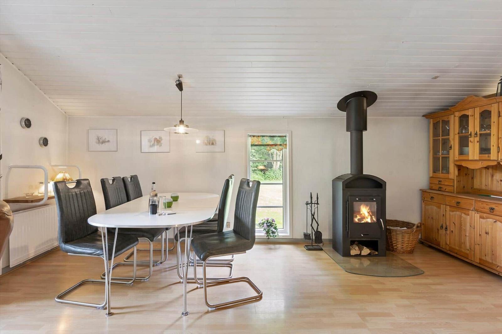 Dining room with table, chairs, wood stove, and wooden furniture.