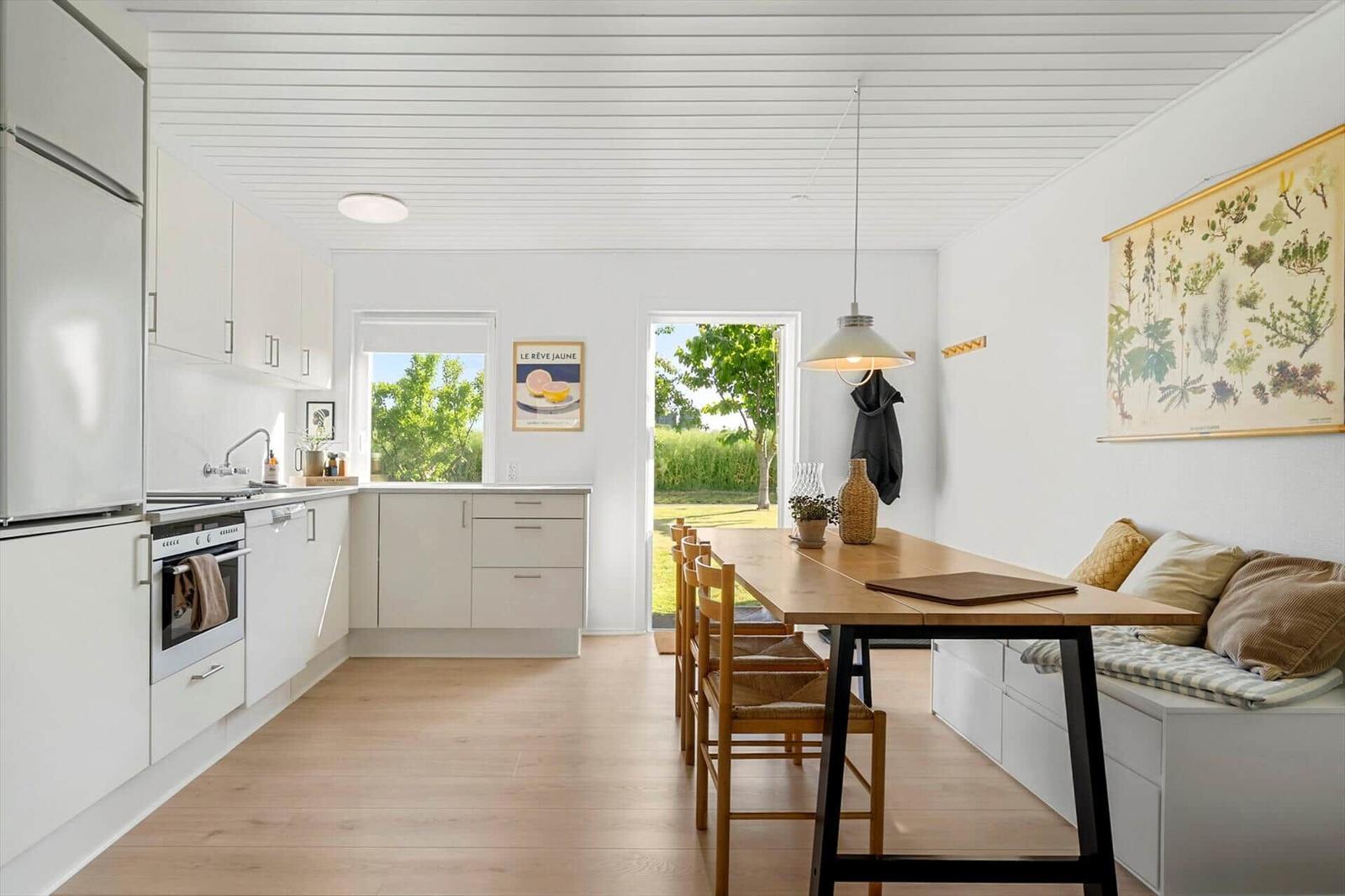 Kitchen with dining area, wooden table, bench, and view of garden.