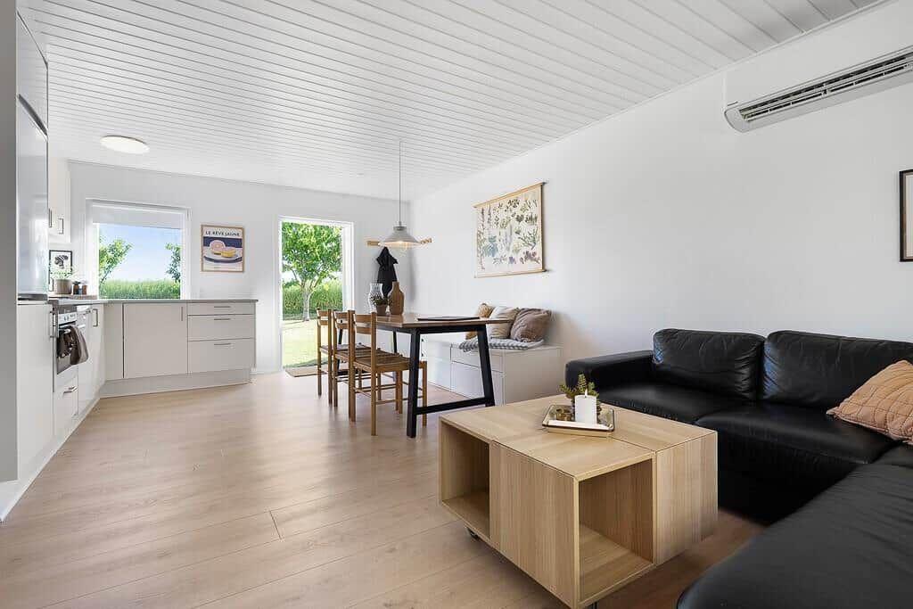 Living and dining area with kitchen, sofa, and table. Passage to terrace.