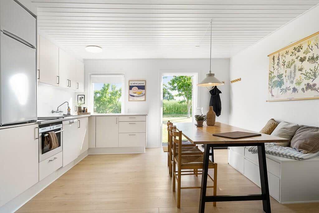 Kitchen with dining area, wooden table, bench, and view of garden.