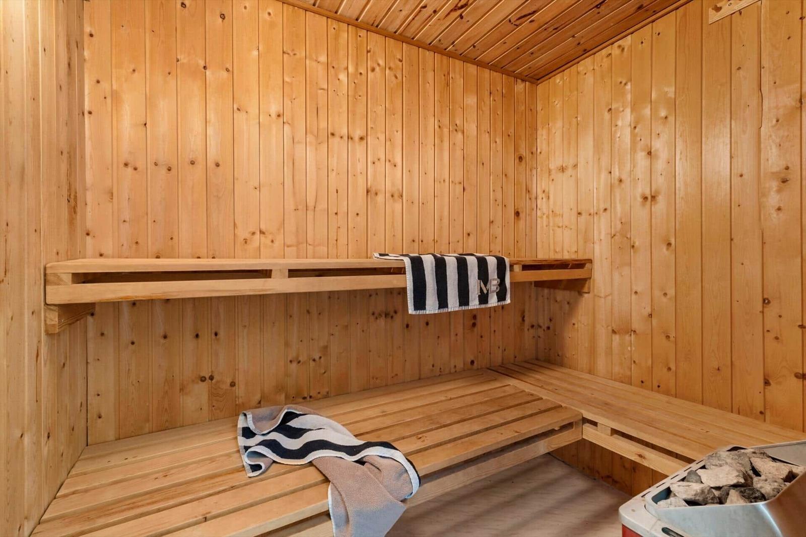 Sauna mit Holzbank und Handtuch. Steinbehälter mit Steinen.