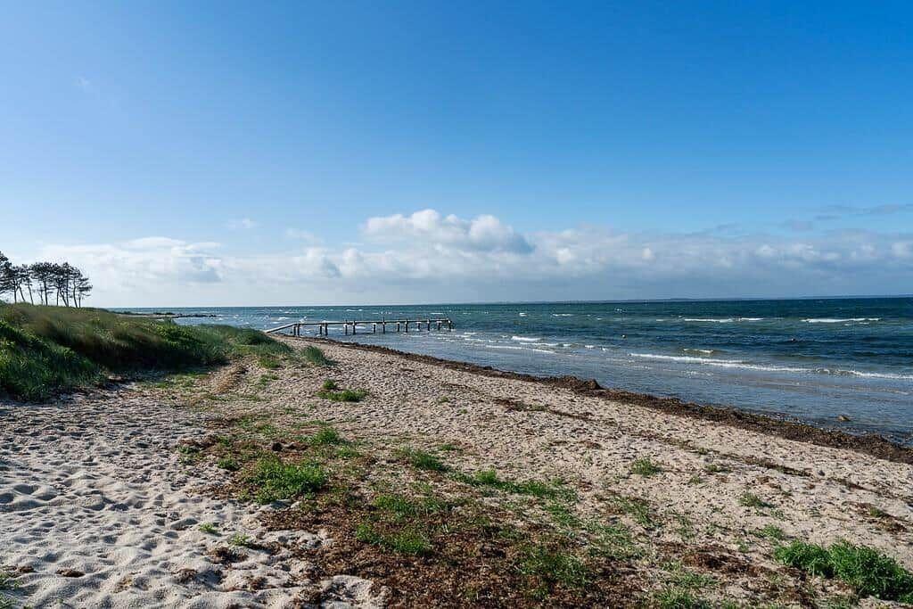 Strand mit Sand, Gras und Holzsteg zum Meer