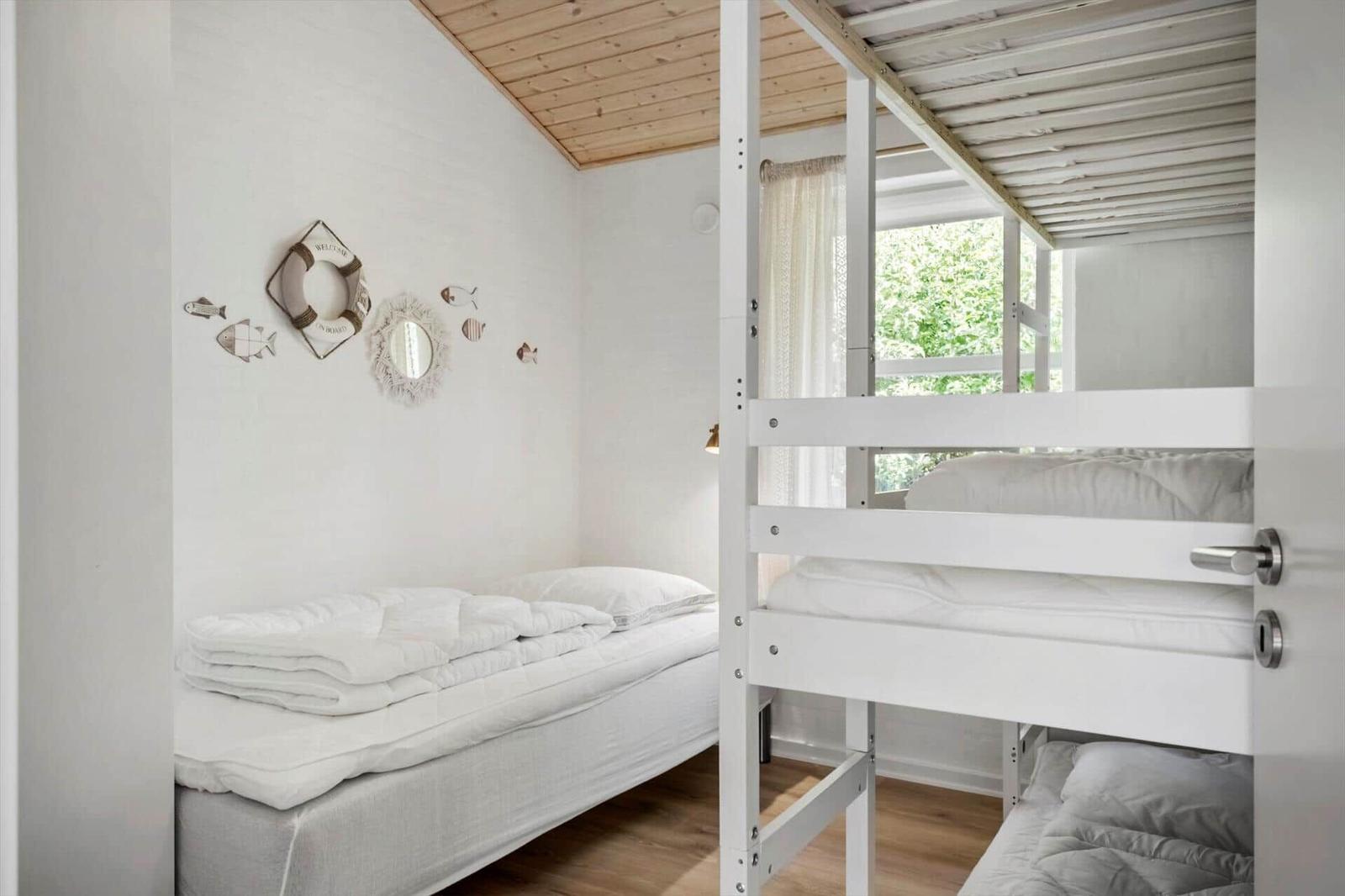 Schlafzimmer mit Doppelbett und Hochbett, Wanddekoration mit Fischmotiven und Fensterblick.