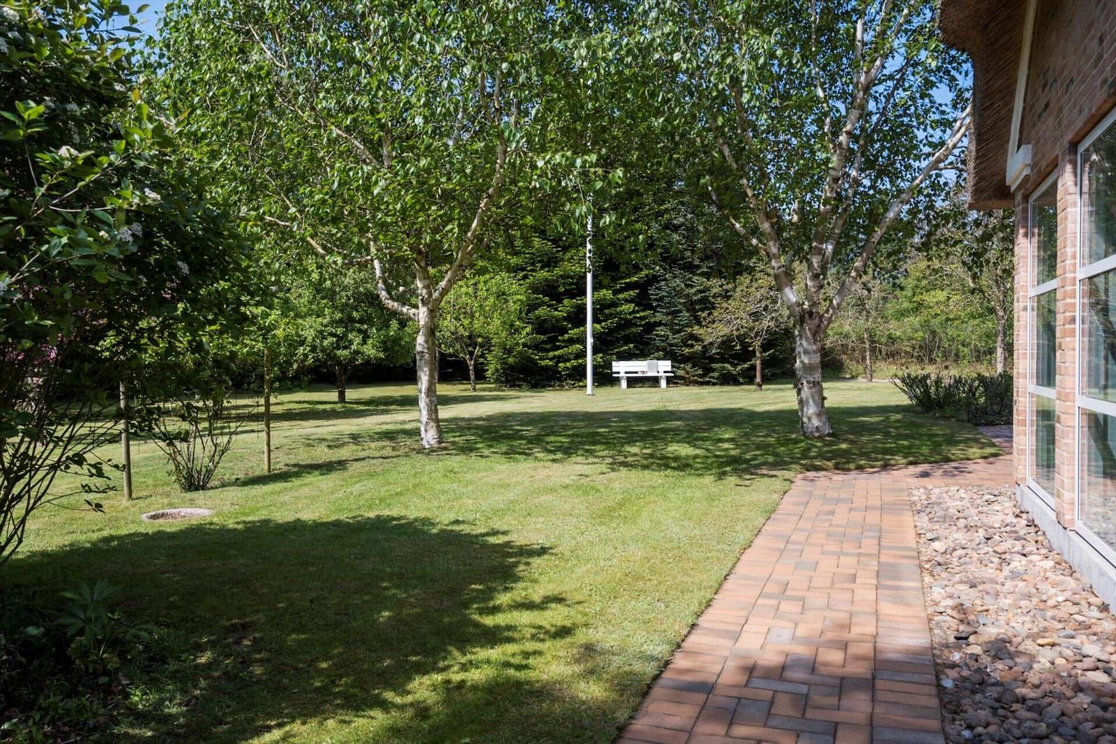 Garten mit Rasen, Bäumen und Steinweg neben Haus