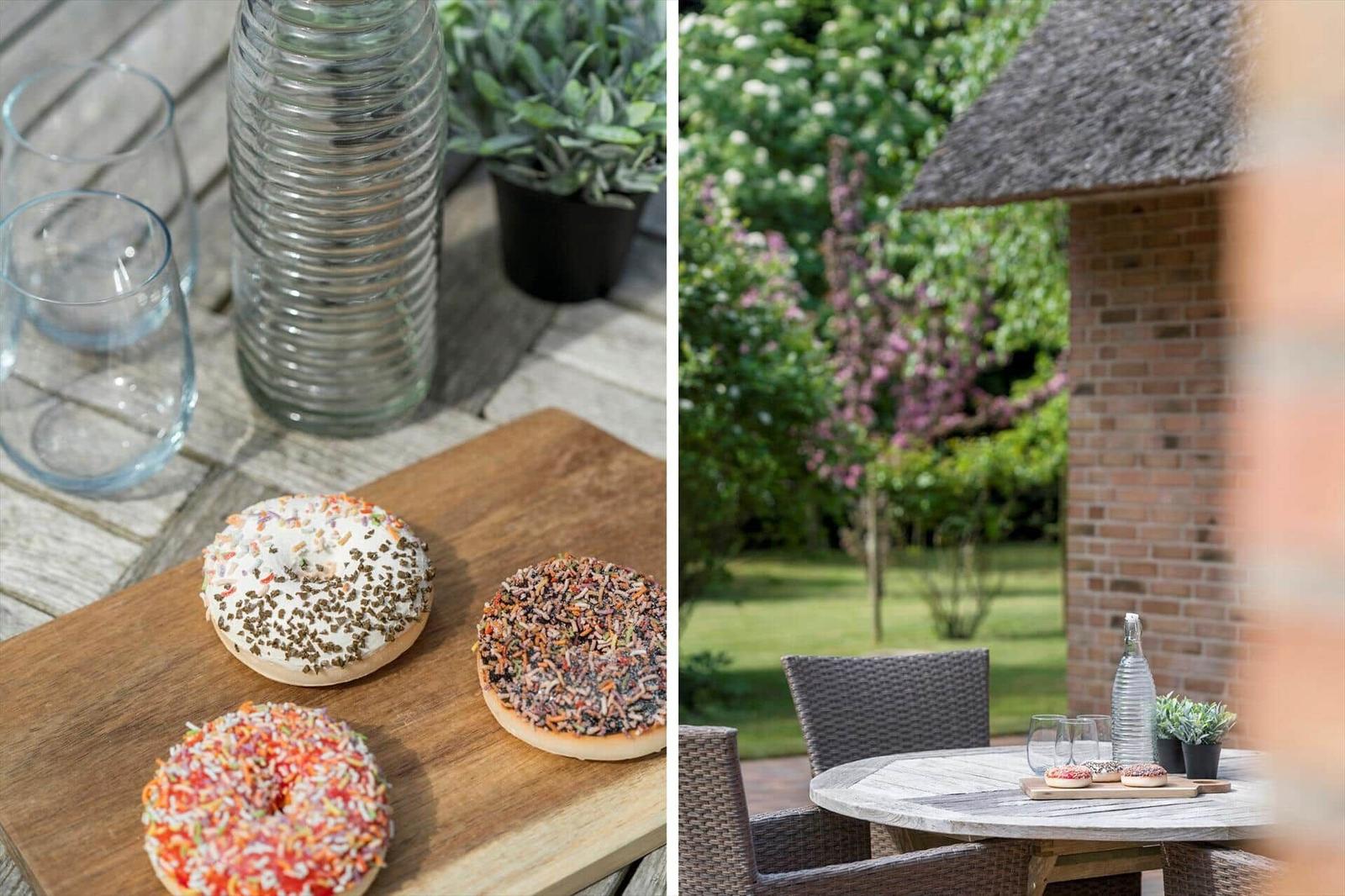 Drei Donuts mit Streuseln auf einer Holzplatte neben Gläsern und einer Wasserflasche.