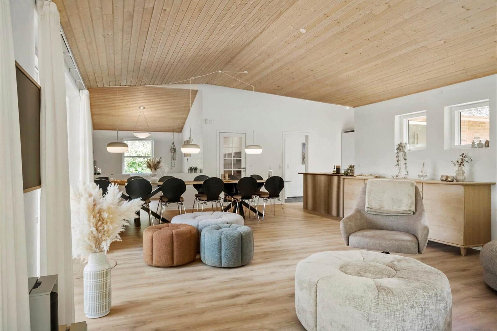 Wohn- und Essbereich mit Holzboden, -decke und modernen Sitzgelegenheiten.
