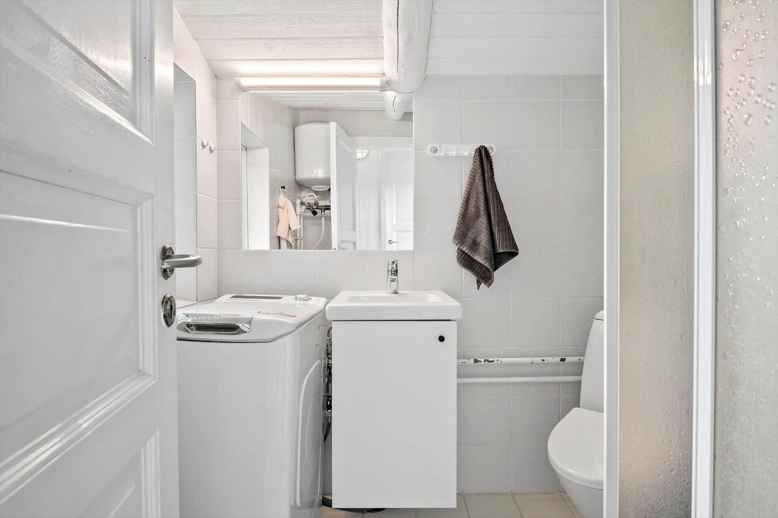 Bathroom with washing machine, mirror, towel, and toilet.