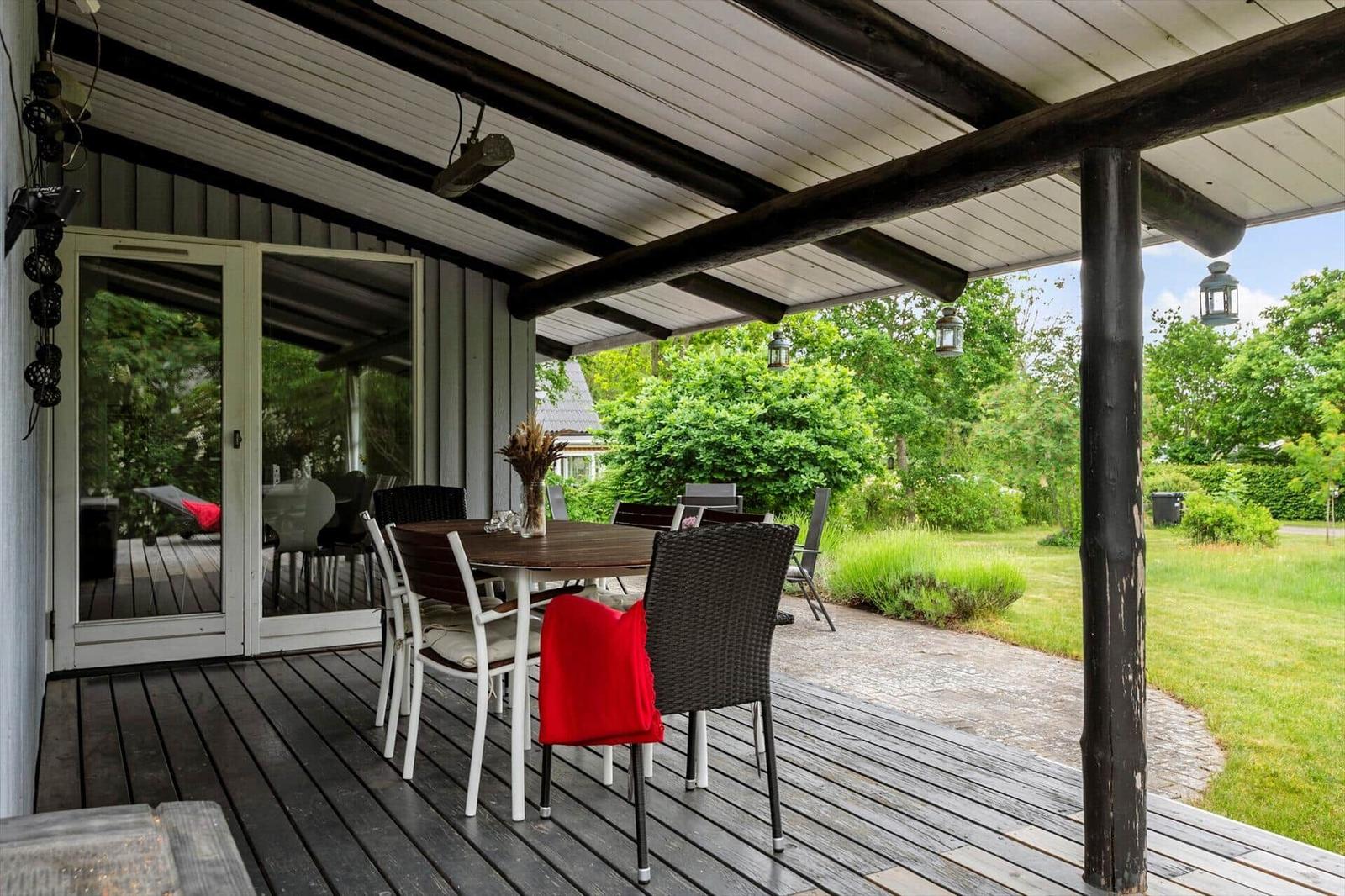 Deck with table and chairs, view of green garden.