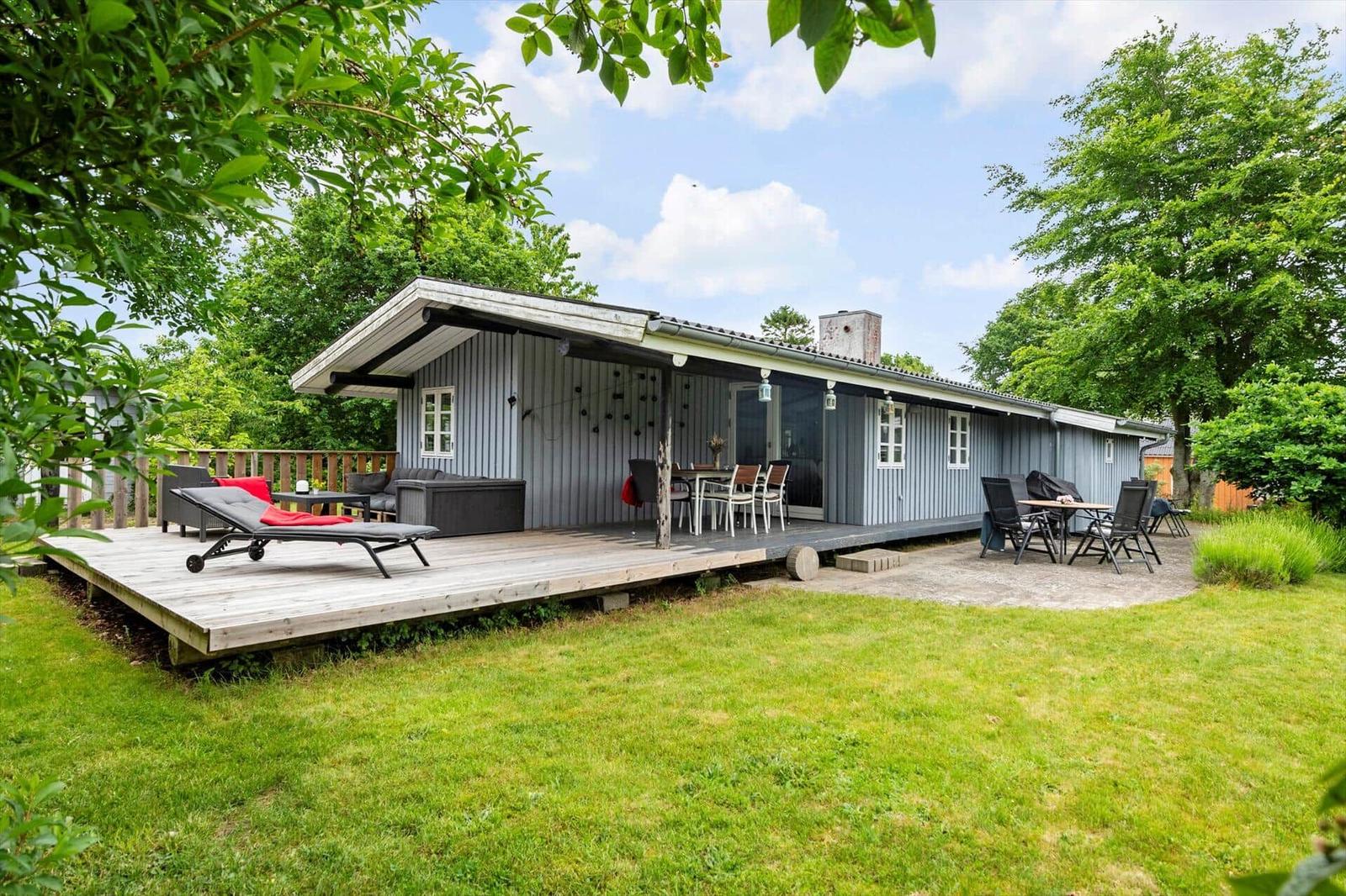 A gray holiday home with terrace and garden. Outdoor seating and grill area are available.