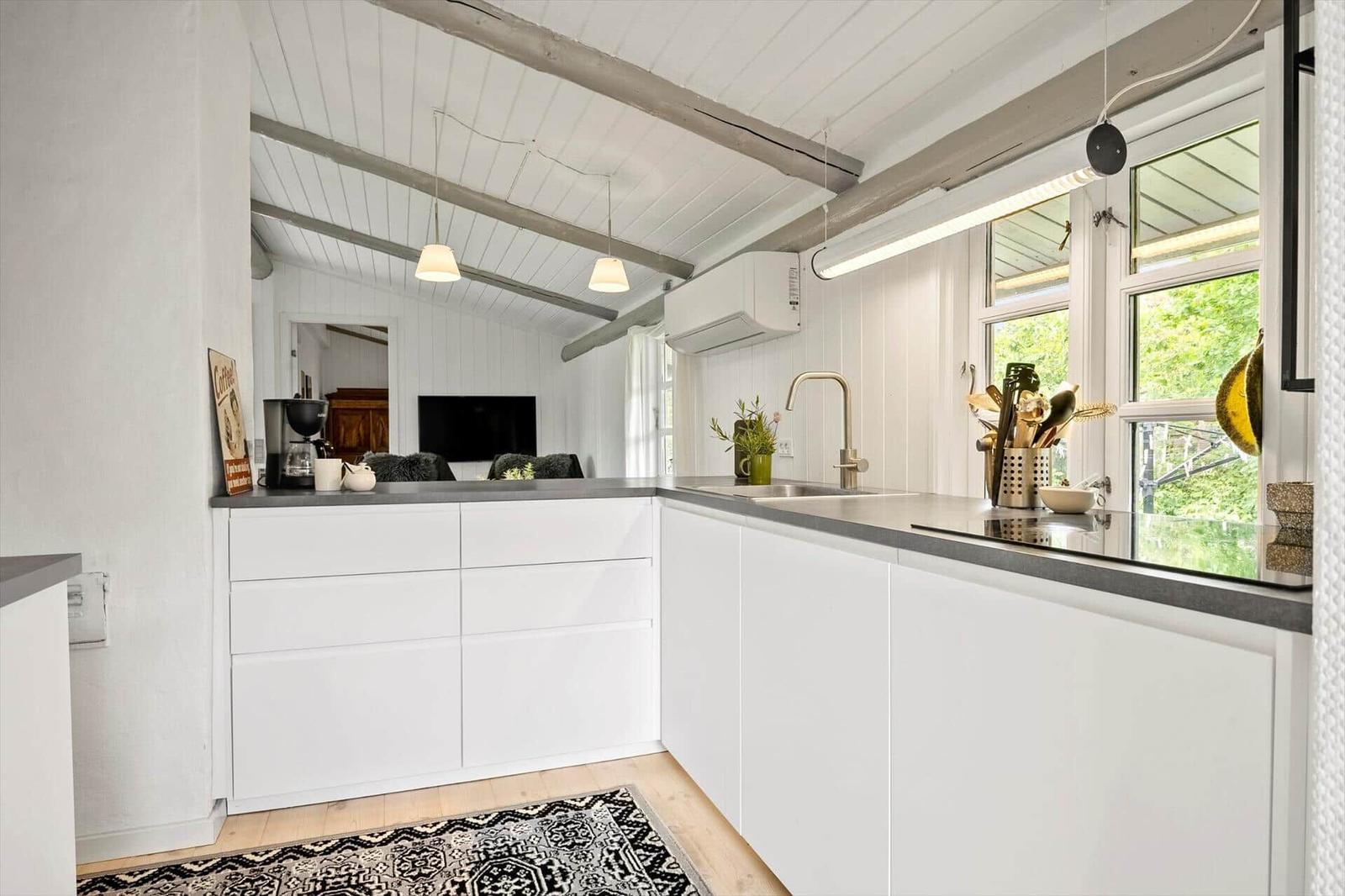 Kitchen with white cabinets, gray worktop, and window view of greenery.