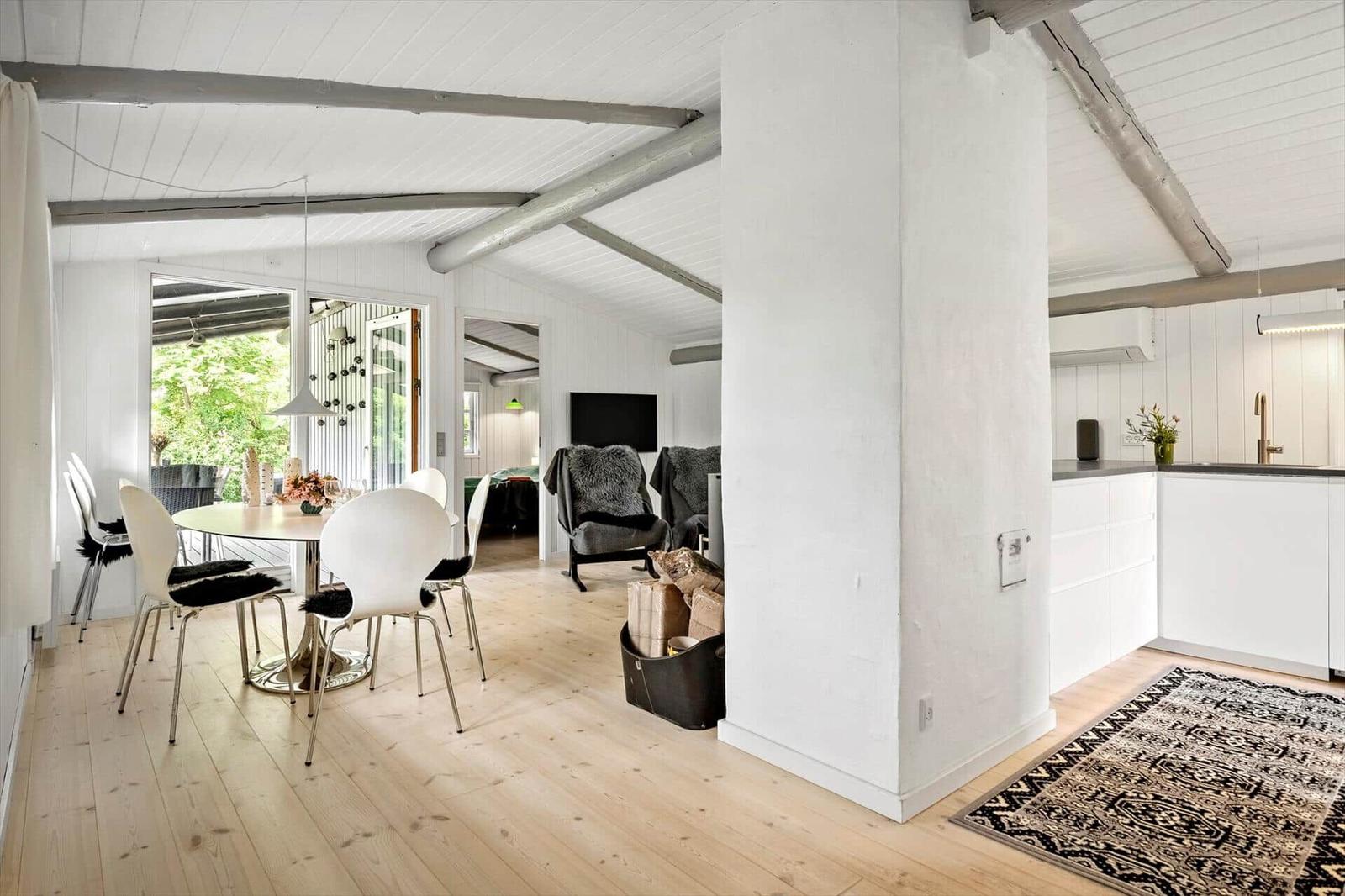 Living and dining area with wooden floor, white kitchen, and dining table with chairs.