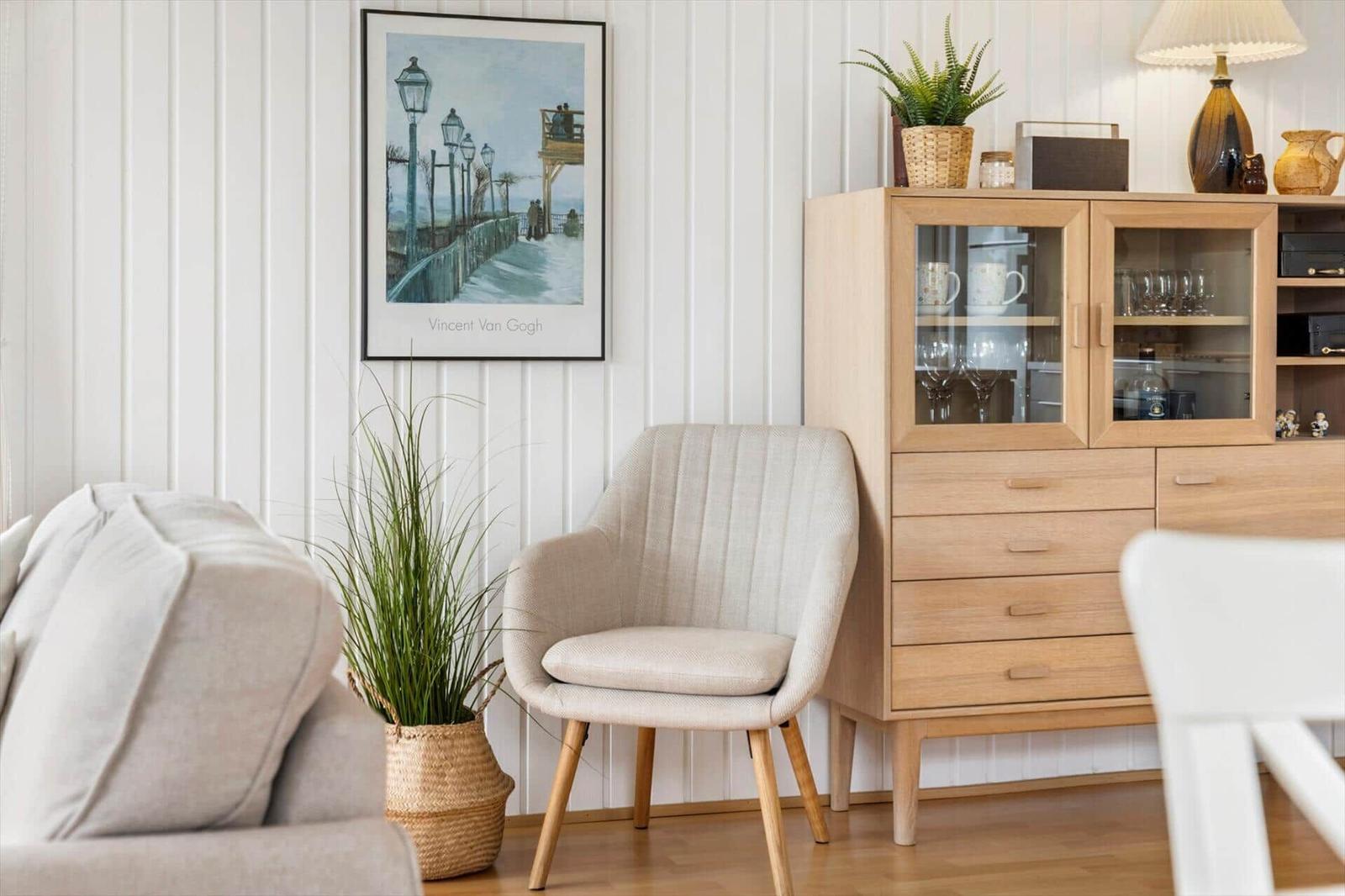 Ein Raum mit einem Sessel, einem Sideboard und einer Wanddekoration.