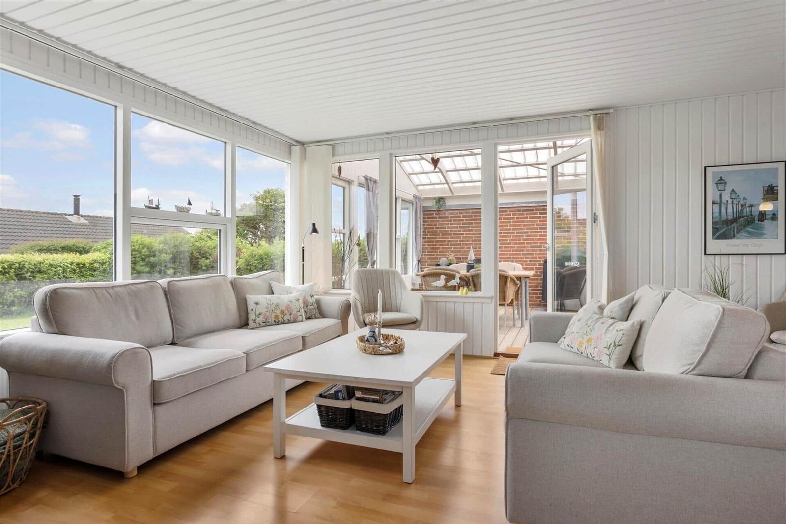 Wohnzimmer mit zwei Sofas, Tisch und Blick auf Garten und Terrasse.