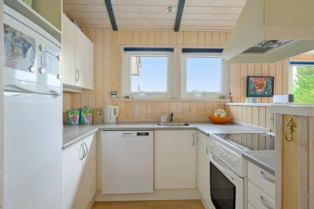 Kitchen with white cabinets, sink, stove, and windows.