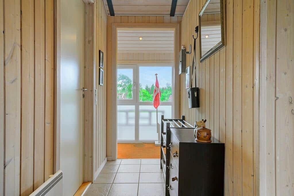 Hallway with wooden paneling, cabinet, and view to balcony with flag.