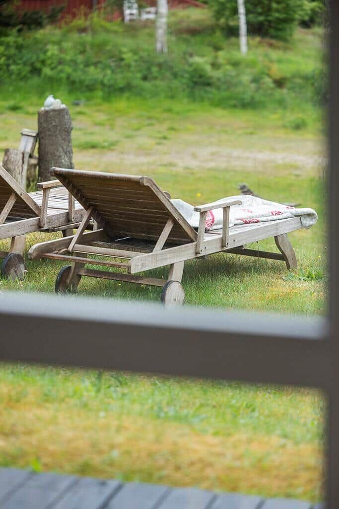 Two wooden lounge chairs with cushions on a lawn
