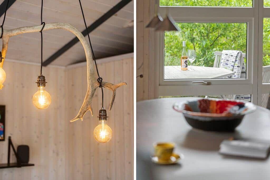 Ceiling light with deer antlers and bulbs. View of terrace with table and wine bottle.