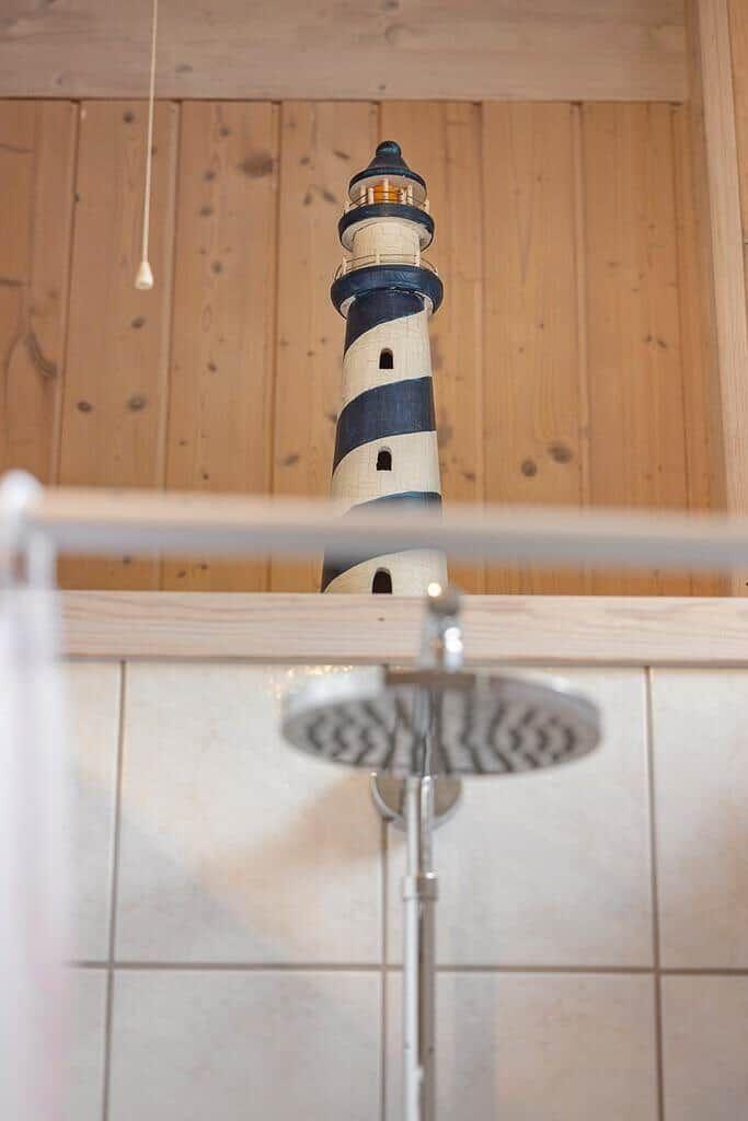 Shower area with lighthouse model against wooden wall