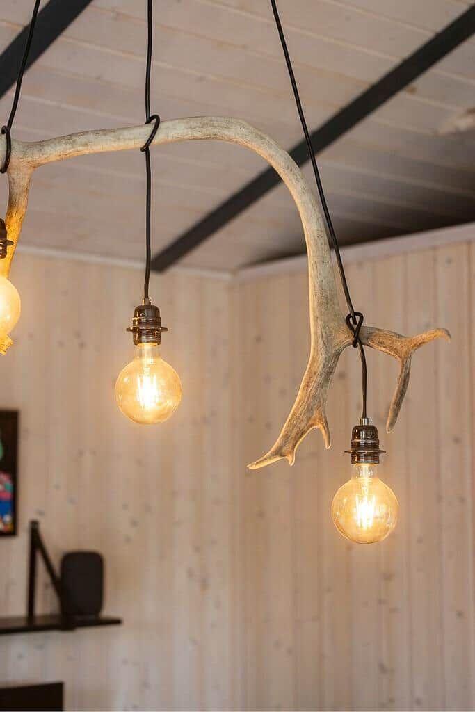 Ceiling light made of deer antlers with three light bulbs.